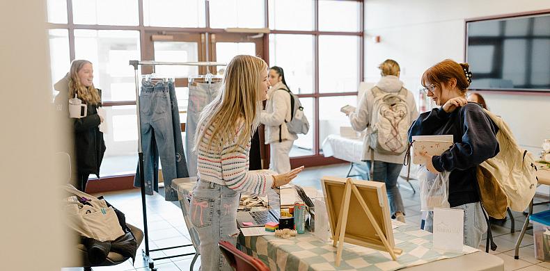 A woman st和s behind a table displayed with her goods at Susquehanna's 学生 Startup Market.